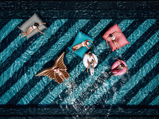 Aerial drone view from above of a beautiful young ladies relaxing on inflatable mattress in the swimming pool and having fun in water on their vacation. Tropical holiday resort