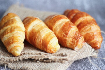 Croissant bread stacked on the table with wooden plates and sackcloth.