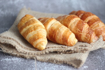 Croissant bread stacked on the table with wooden plates and sackcloth.