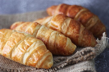 Croissant bread stacked on the table with wooden plates and sackcloth.