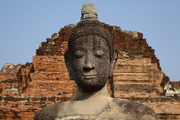 Head and shoulders of Buddha statue at Wat Mahathat with the ruins in the background (horizontal image), Ayutthaya, Thailand