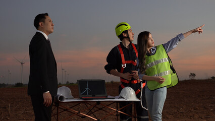 A beautiful engineer and a young technician are presents a report of the turbine to the manager with computer graphics on twilight time.