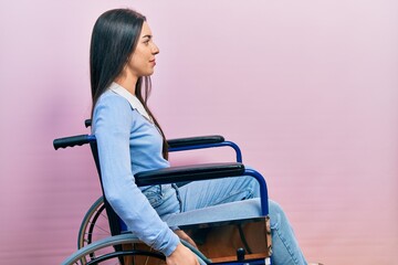 Beautiful woman with blue eyes sitting on wheelchair looking to side, relax profile pose with...