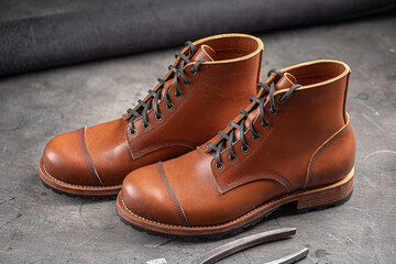 Handcrafted brown leather shoes with cobbler tools on the backgound