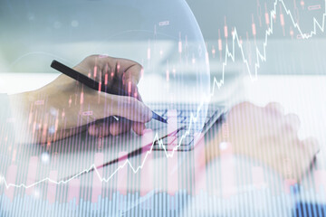 Abstract creative financial graph with world map and with hand writing in notebook on background with laptop, forex and investment concept. Multiexposure