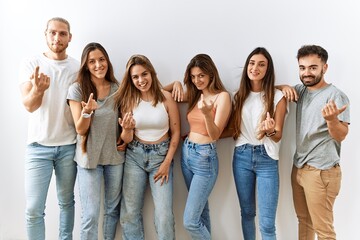 Obraz premium Group of young friends standing together over isolated background beckoning come here gesture with hand inviting welcoming happy and smiling