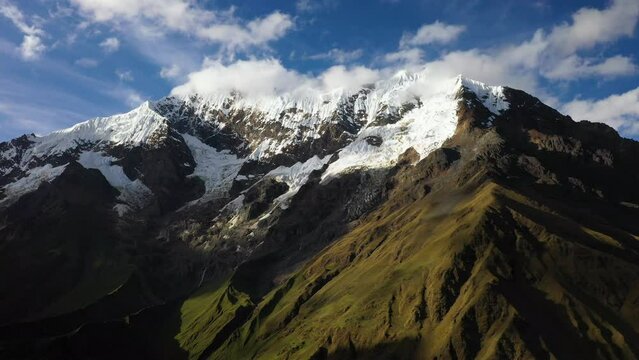 Epic cinematic drone shot of the Andes Mountains in South America, with snow capping the top of Aconcagua peak, blue skies with partial clouds