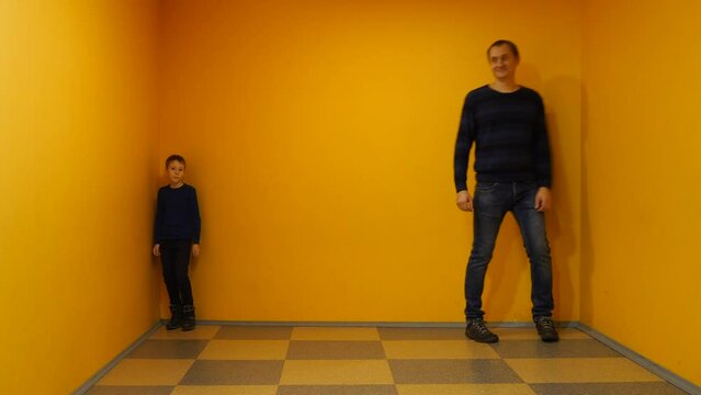 Optical Illusion with People Growth. Ames room. Father and Son in Scientific Children's Center. Scientific Experiment About Optical Illusion While Boy Became Higher than Man in the Same Perspective