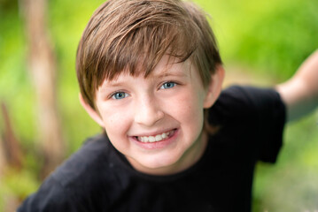 portrait of smiling european happy boy. outside on a green background