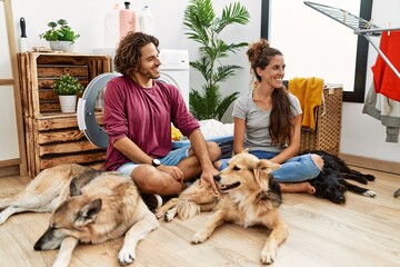 Young hispanic couple doing laundry with dogs looking away to side with smile on face, natural expression. laughing confident.