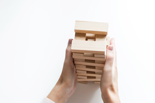 Board game geng or tower on a white table. The hand of a man collects it