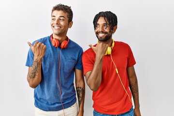 Young hispanic brothers standing over isolated background wearing headphones smiling with happy...
