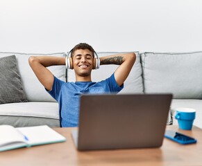 Young hispanic man listening to music on laptop at home