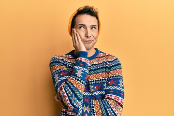 Fototapeta premium Young handsome man wearing wool hat and colorful sweater thinking looking tired and bored with depression problems with crossed arms.