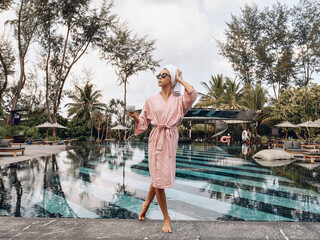 Portrait of a wealthy and confident woman wearing a bathrobe, sunglasses and a towel on her head...