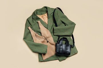 Green classic jacket and beige women's top with bag. Women's stylish autumn or spring trendy clothes. Fashion concept. Flat lay, top view.