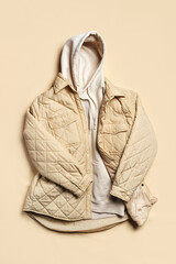 Quilted  jacket with white hoody on beige background. Fashion sweatshirt, casual youth style,...