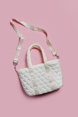 White soft textile quilted bag on a pink background. Sylish handbag. Trendy accessories. Fashion...