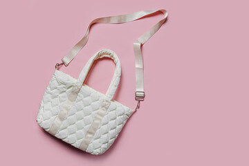 White soft textile quilted bag on a pink background. Sylish handbag. Trendy accessories. Fashion concept. Flat lay, top view. © igishevamaria