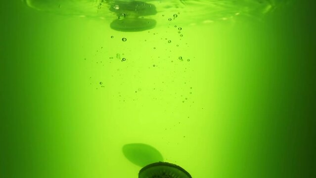 Kiwi falls into the juice. Slow motion 240 frames. Green juice. Fresh fruit