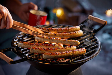 Man taking grilled sausage from barbecue