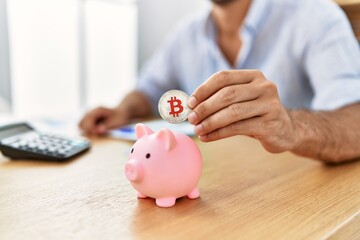Businessman insert bitcoin in piggy bank at the office.