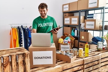 Young hispanic volunteer man smiling happy working at charity center.