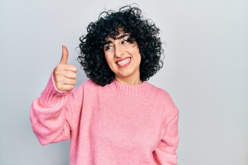 Young middle east woman wearing casual clothes looking proud, smiling doing thumbs up gesture to the side