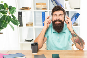 Happy man listening to melody in headphones in office, music