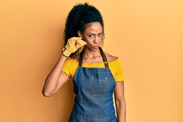 Middle age african american woman wearing professional apron mouth and lips shut as zip with...