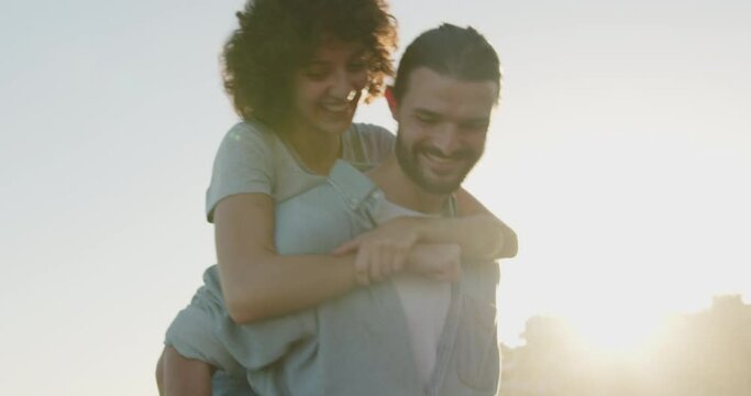 Three young friends walking on street and giving piggyback ride in sunset