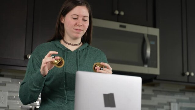 Smiling woman takes remote lesson to learn finger cymbals online on a laptop. Remote learning concept.
