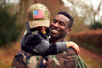 American Soldier In Uniform Returning Home To Family On Leave With Son Wearing Army Cap