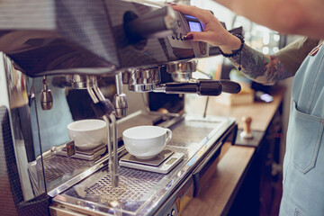 Fototapeta na wymiar Female barista using coffee machine in cafeteria