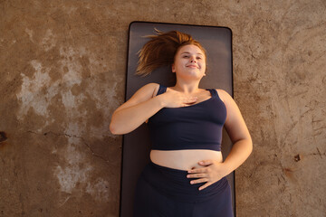 Young ginger woman doing breathing exercise during yoga practice