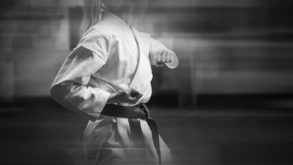 Young sportswoman in karate training. Added blur effect for more motion effect. Retro style with imitation film grain. Black and white.