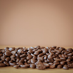 Heap of roasted coffee beans on wood desk with brown background 