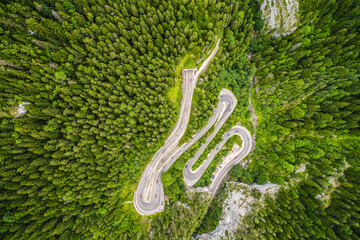 Amazing mountain winding road in Romania. Aerial view of Bicaz Gorges in the summer landscape with a curved motorway between the tall mountains and the green forest.