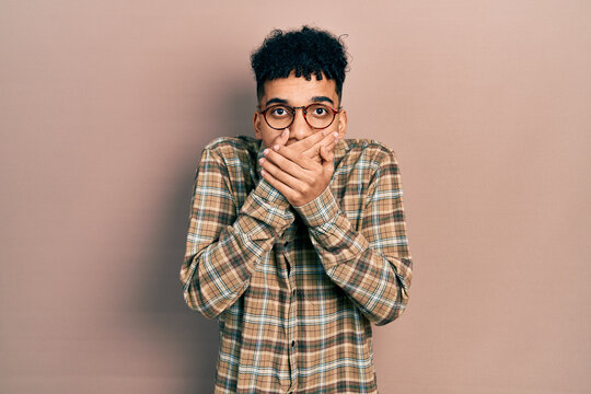 Young african american man wearing casual clothes and glasses shocked covering mouth with hands for mistake. secret concept.