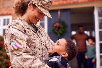 American Female Soldier In Uniform Returning Home To Family On Hugging Children Outside House