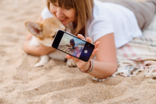 Senior woman taking photo on cellphone while resting with her dog