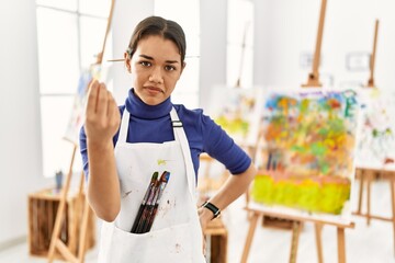 Young brunette woman at art studio doing italian gesture with hand and fingers confident expression