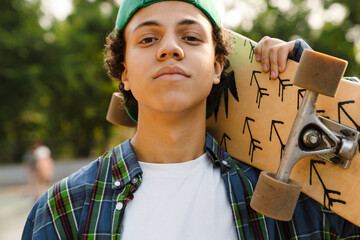 Hispanic boy holding skateboard while spending time at skate park © Drobot Dean