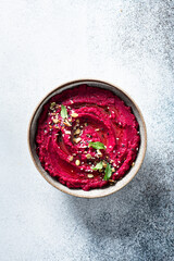 beet hummus in a ceramic bowl on a light background, top view