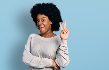 Young african american woman wearing casual clothes smiling with happy face winking at the camera doing victory sign. number two.