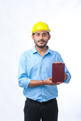 Young indian engineer or student wearing hardhat and showing diary on white background.