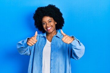 Fototapeta na wymiar Young african american woman wearing casual clothes approving doing positive gesture with hand, thumbs up smiling and happy for success. winner gesture.