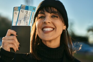 Young hispanic woman smiling happy passport and boarding pass at the city.