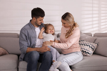 Family with little daughter spending time together on sofa at home