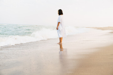 Young woman wearing dress looking at sea during walking on beach